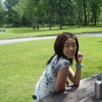 angela fan sitting at picnic table in grassy park