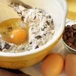 chocolate chip cookie ingredients mix and egg in a bowl with bowl of chips