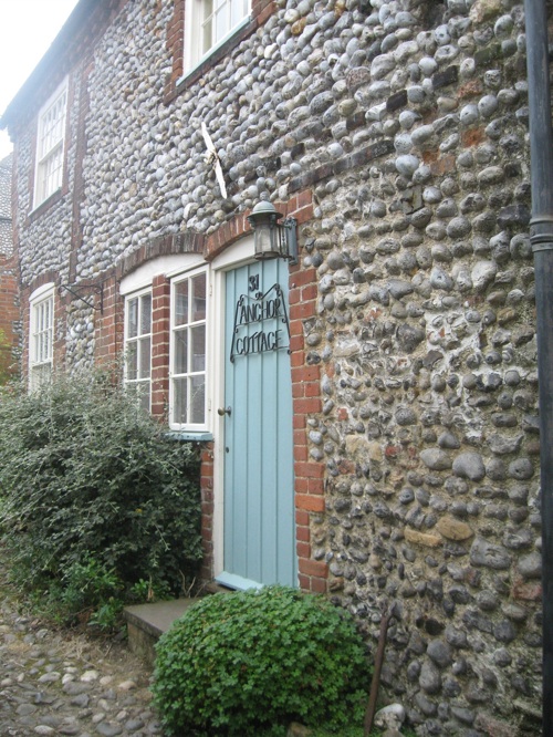 anchor cottage old stone building with robins egg blue door and name in iron 