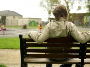 teenage boy on bench with his back facing us