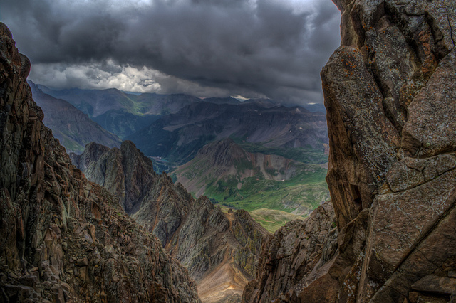 view of moutnains from higher up on a taller rocky landing, clouds in sky