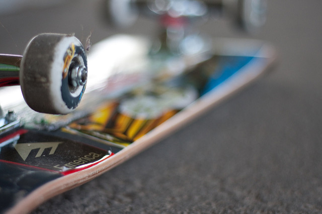 skateboard upside down with focus on one of the wheels, stickers on bottom