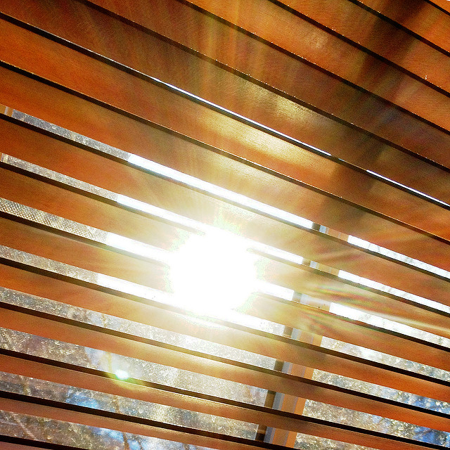 sun shining through closed mini-blinds on window