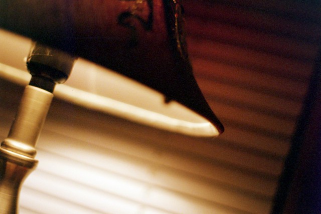 lamp shade by bed with miniblinds, light on