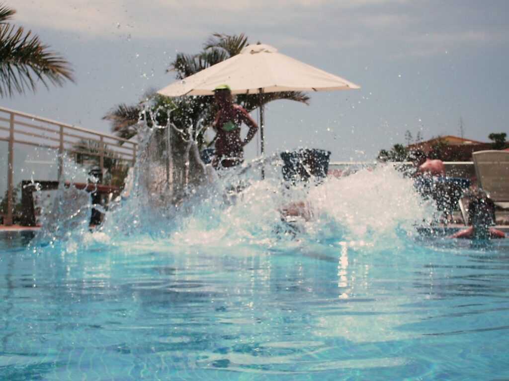 image of big splash in outdoor pool, plam trees in distance