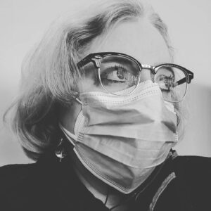 Black and White headshot of Sarah Einstein wearing a mask. 