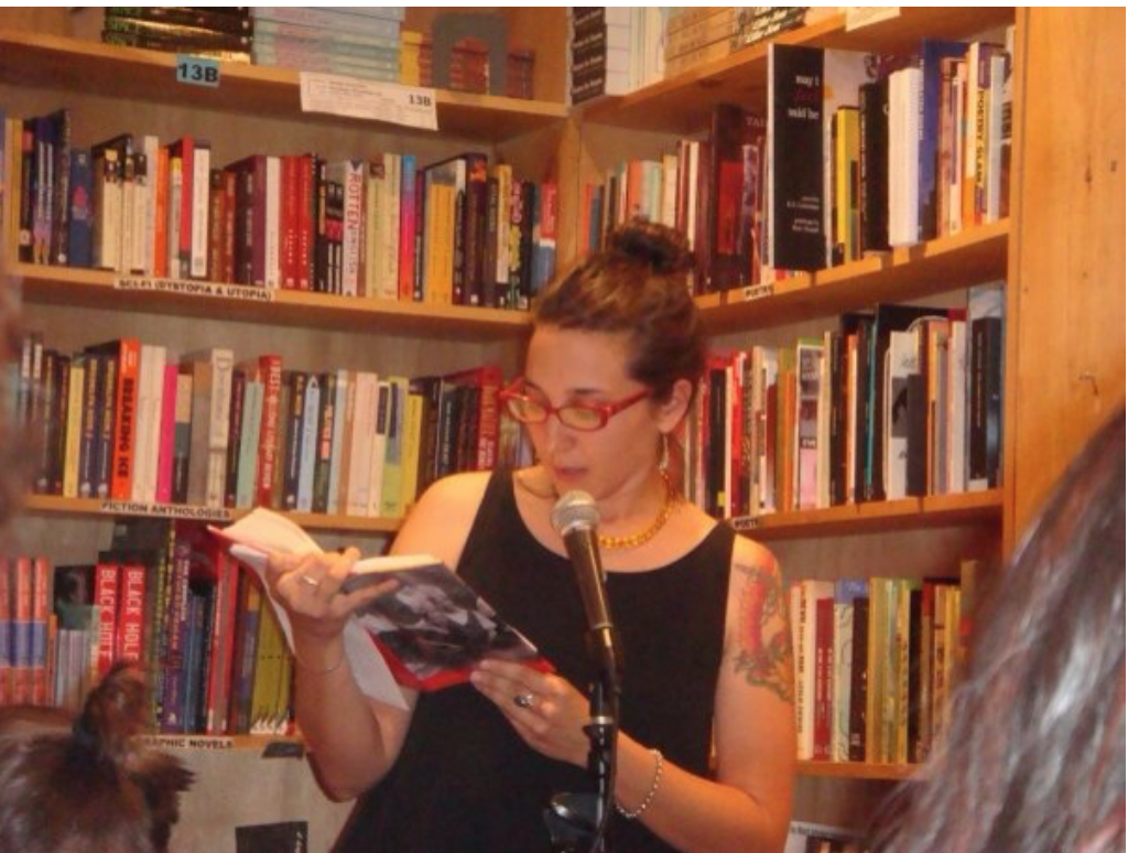 Author Sonya Huber reading from a book in a library.