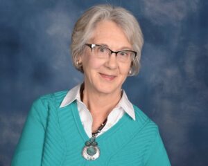 Sandra Eliason's headshot shows a Woman in a turquoise shirt
