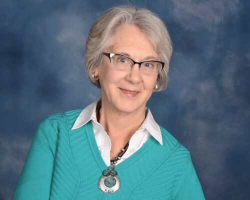 Sandra Eliason's headshot shows a Woman in a turquoise shirt