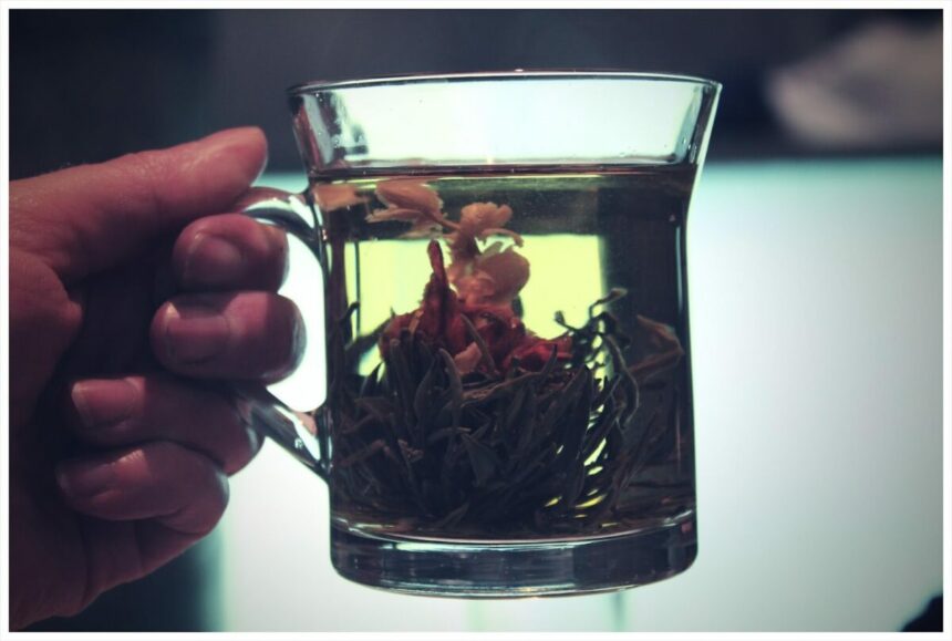 A hand holding a glass of herbal tea