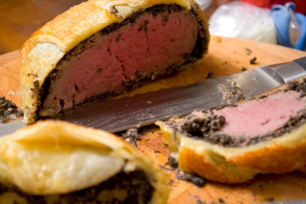 sliced beef wellington - pink beef inside doughy shell
