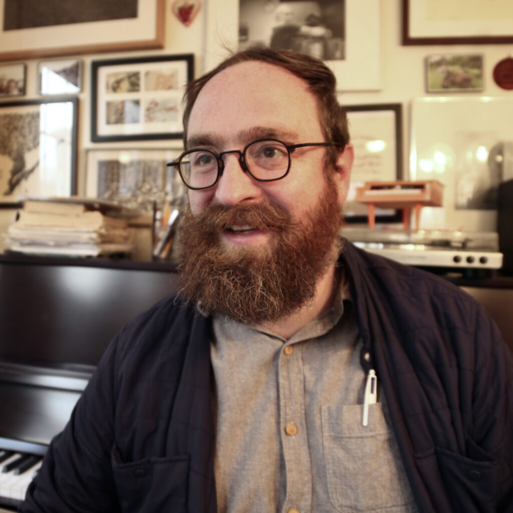 Headshot of Author John West, a white man with glasses and a full, reddish-brown beard.