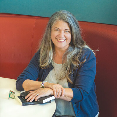Headshot of Dorothy Rice, a white woman who has long salt and pepper hair and is smiling.