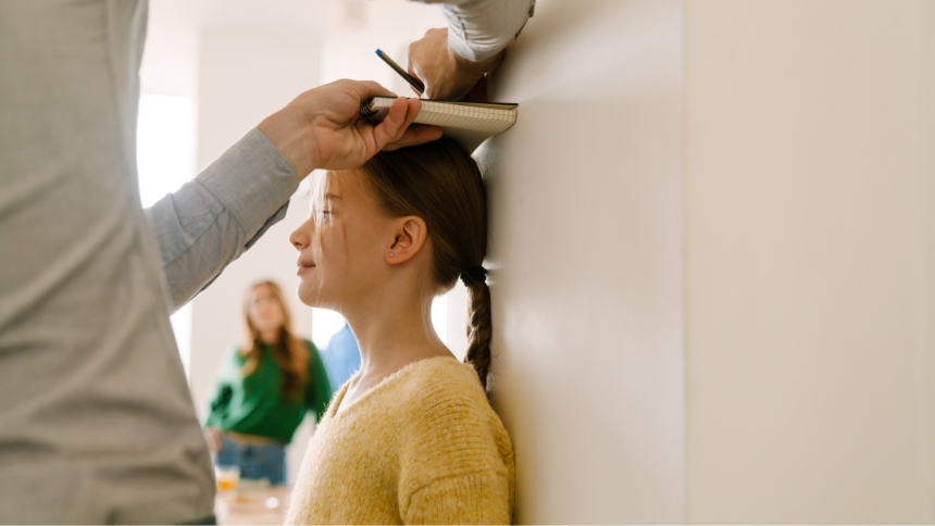 A person measuring a child's head against a wall