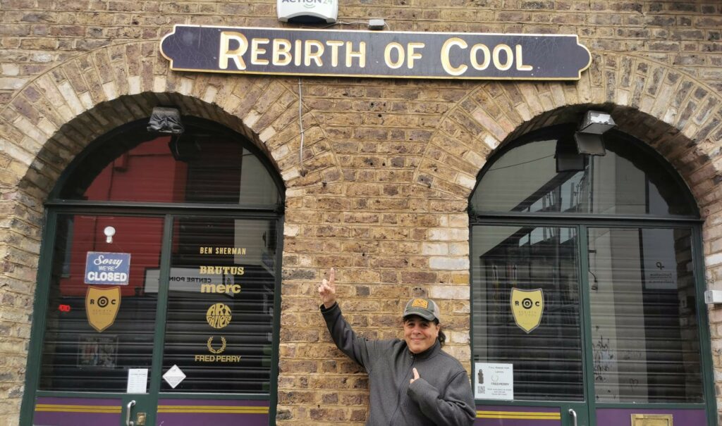 ralph greco jr pointing to "rebirth of cool" sign