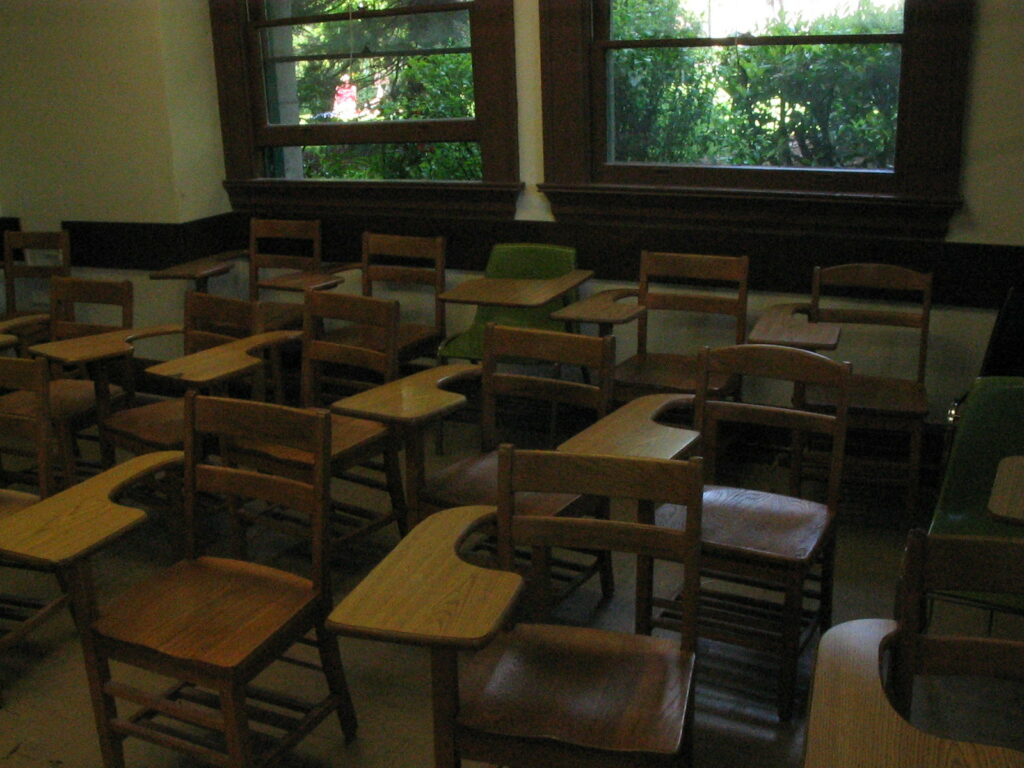classroom interior, older style desks with big wooden windows behind
