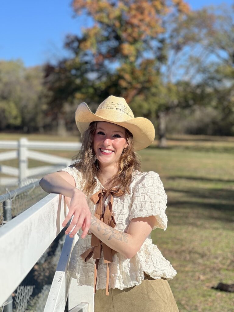 Tori Walters in cowboy hat leaning on fence