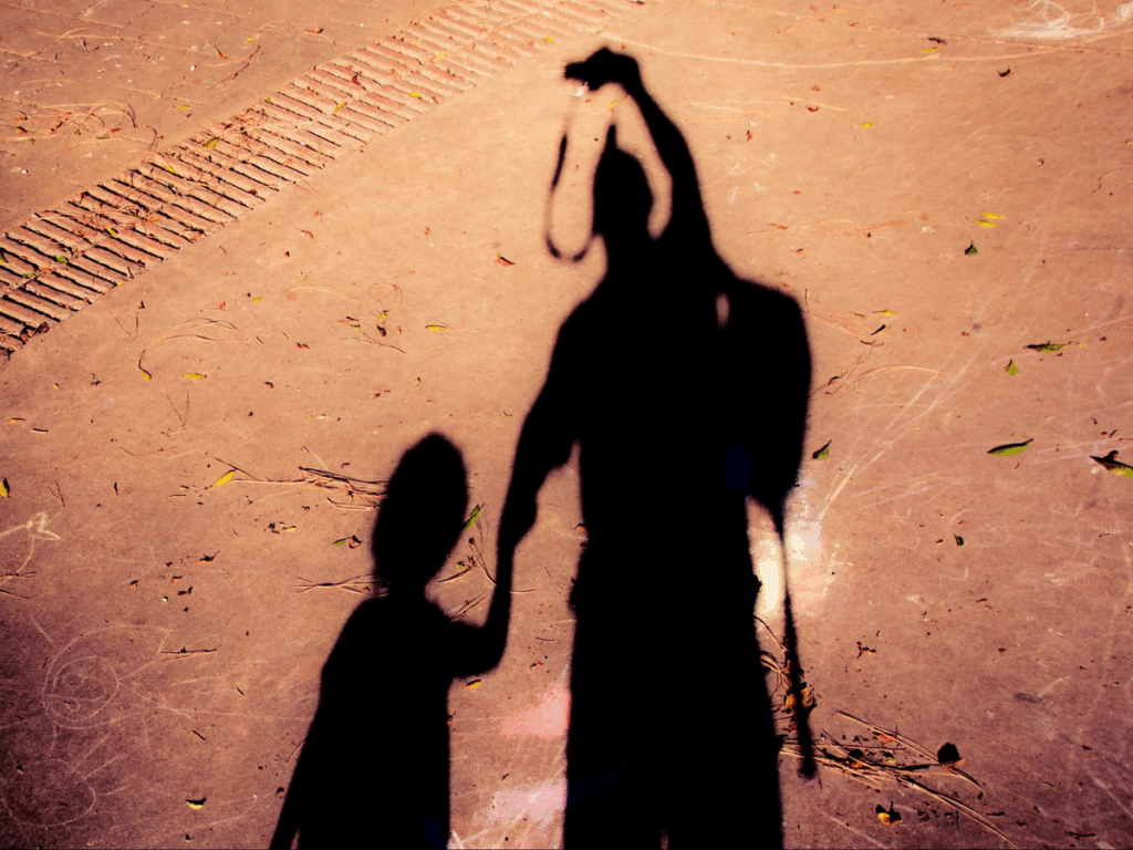 shadow of parent and child holding hands, with parent taking photo with camera, strap is also a shadow