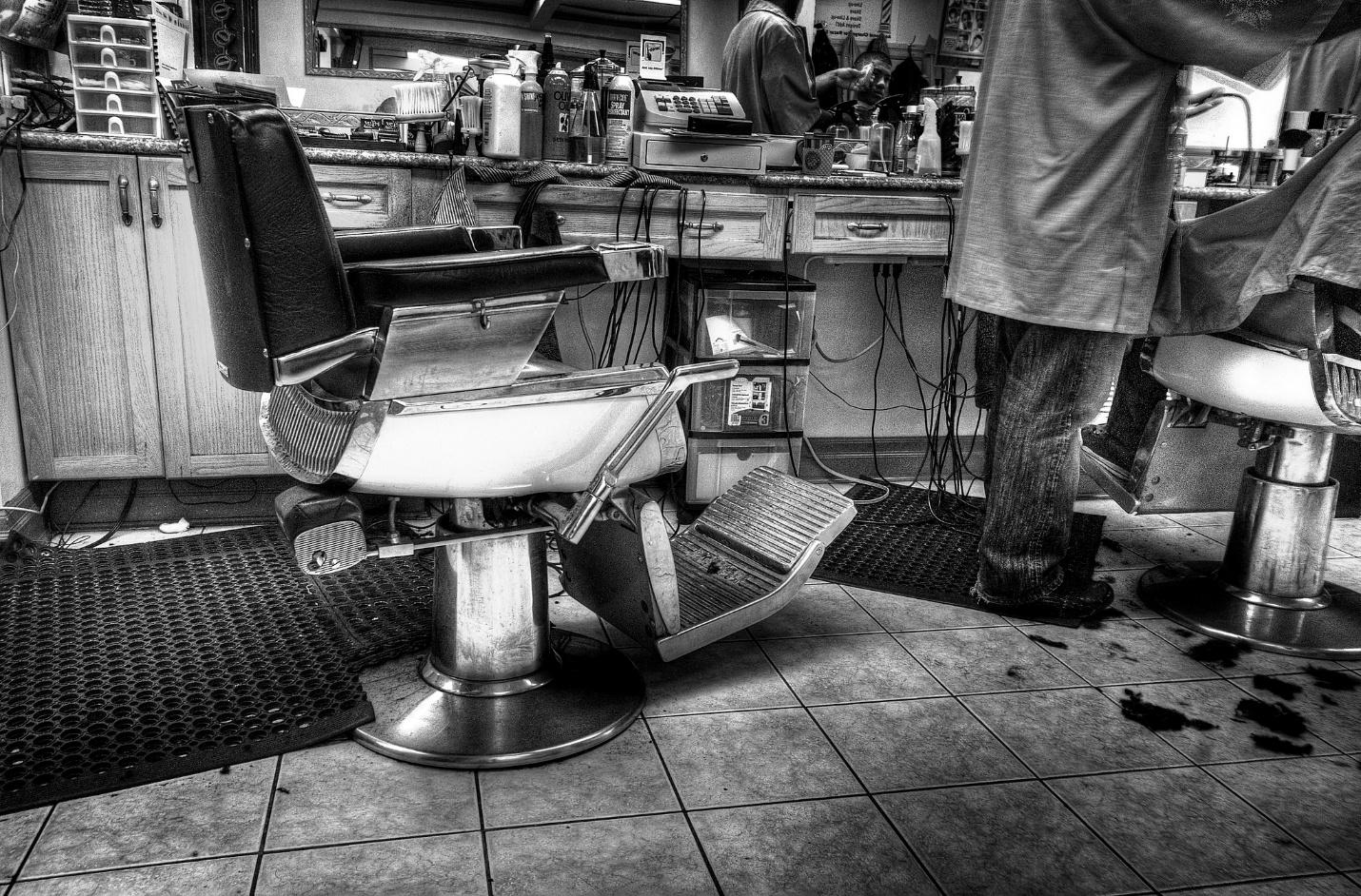 A barber shop with a chair; older-style wooden cabinetry and vintage chairs