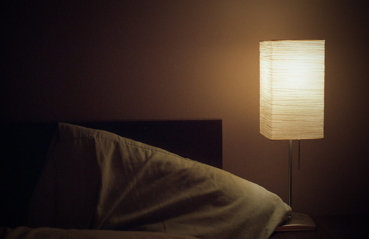soft glow of lamp next to a bed