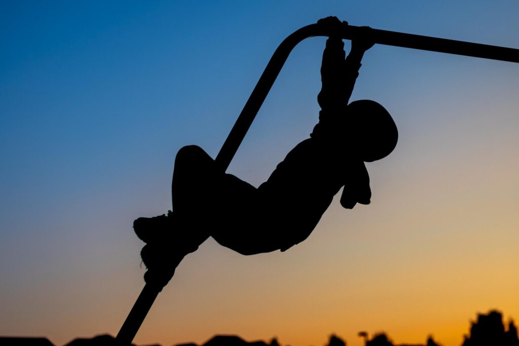 silhouette of child on money bars at sunset