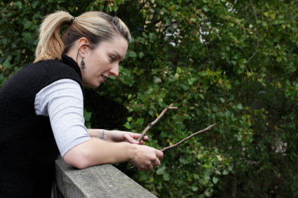 girl holding two twigs over bridge