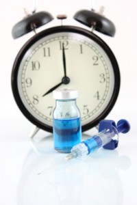 Clock with bottle and syringe to signify waiting for a cure