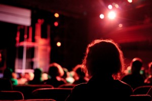 blurry image of heads facing a theatre stage