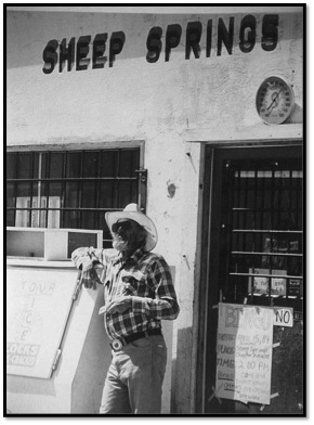Older man in cowboy hat in front of sheep springs trading post