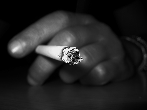 Close up of lit cigarette about to ash male hand