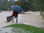 man in umbrella standing in flooding street