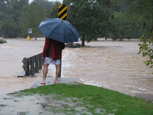 Man in umbrella standing in flooding street