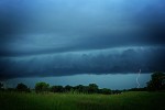 thunderstorm over meadow dark clouds single streak of lightening