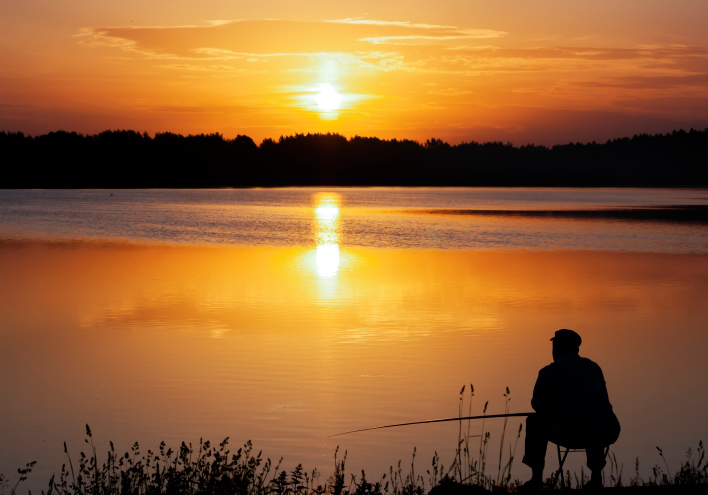 Fisherman silhouette at lake at dawn
