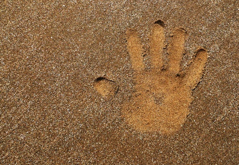 kid's hand print in the sand