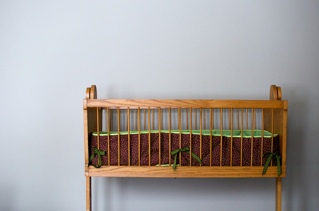 Crib left of center in photo empty bumper with green ribbons