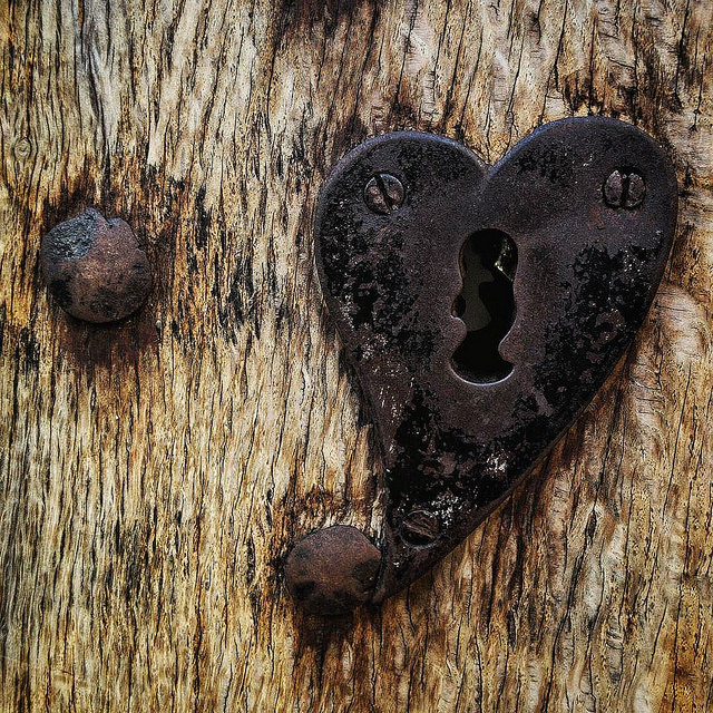 rustic wood door with rusty nail and heart-shaped lock