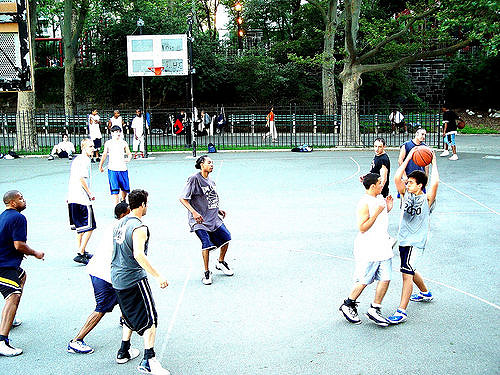 Crowd of younger adults and teens playing basketball several races together