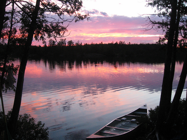 Canoe on side of lake sunset in back