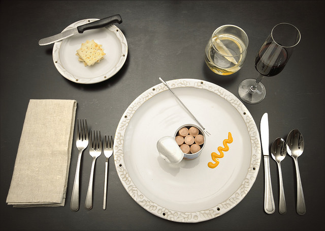 Vienna sausages n can on fancy plate and formal place setting with wine an ironic photo