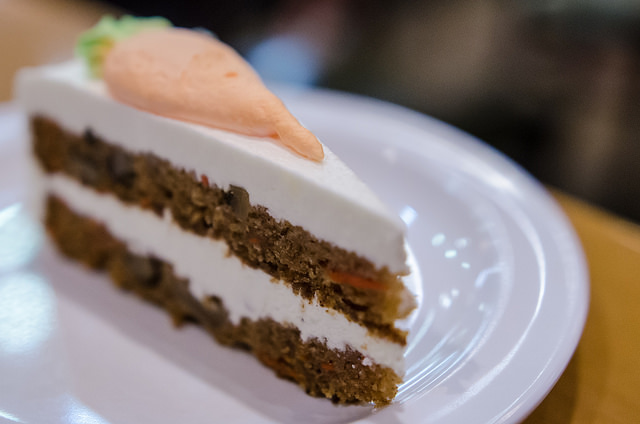 single slice of carrot cake on plate, carrot-shaped design made of icing