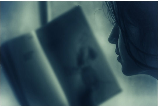 close up of woman looking into a book and holding it in front of her face