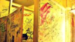 bar bathroom stall covered in various graffiti