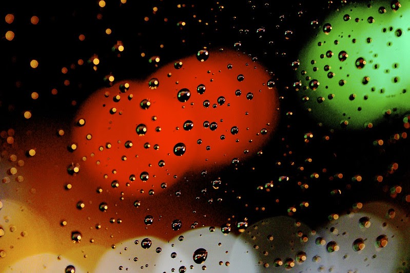 Blurry red and green lights through a rainy windshield