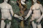 statues of adam and eve in garden, holding an apple between them, belly buttons showing