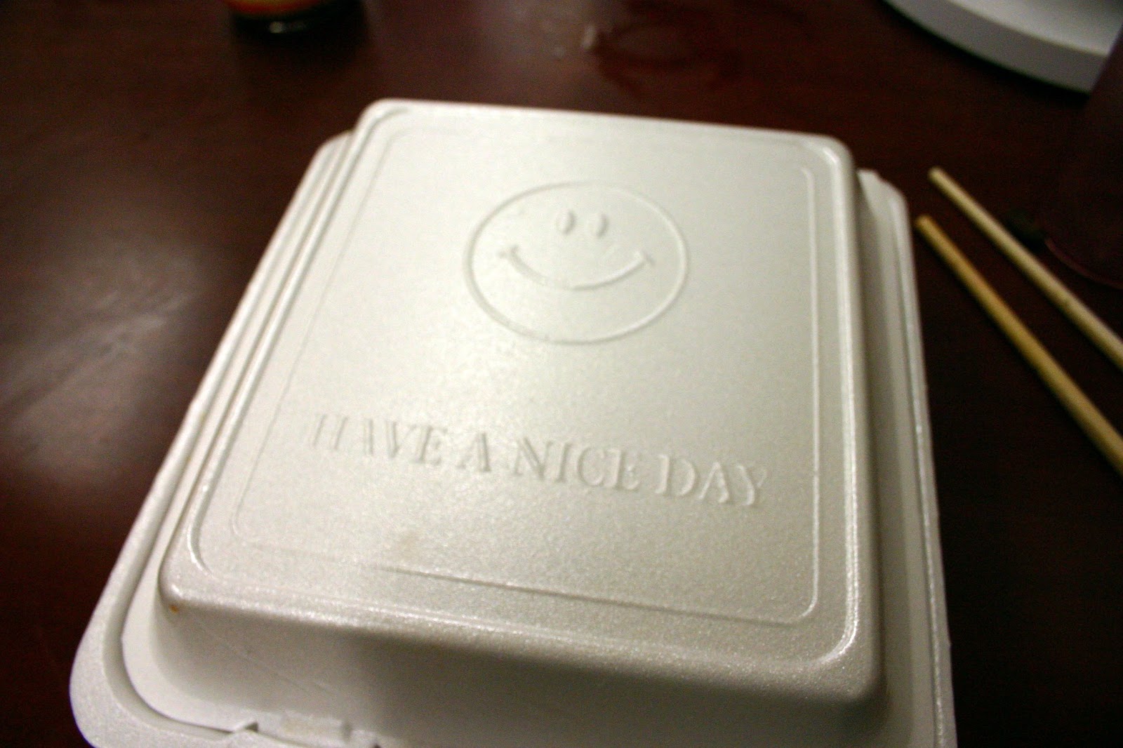 styrfoam to-go box, closed, with smiley face and "have a nice day" on it