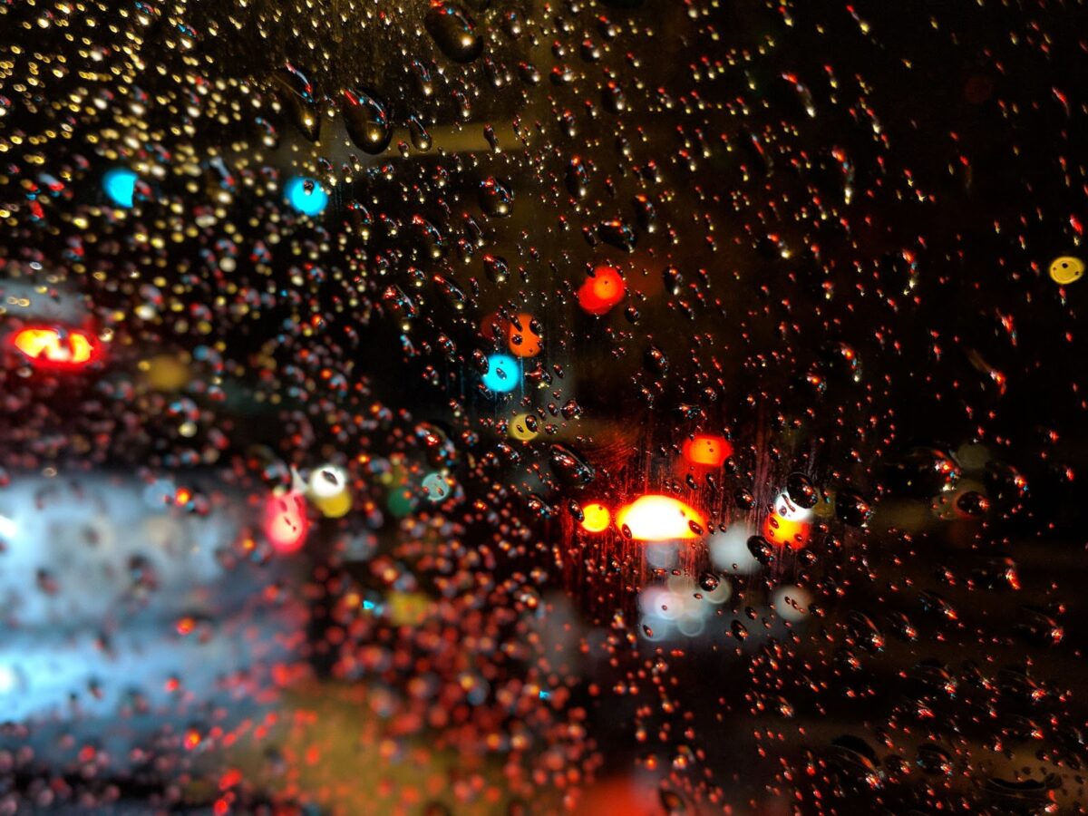 abstract picture of red and green lights shining through wet car windshield