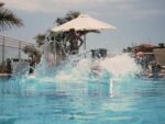 image of big splash in outdoor pool, plam trees in distance