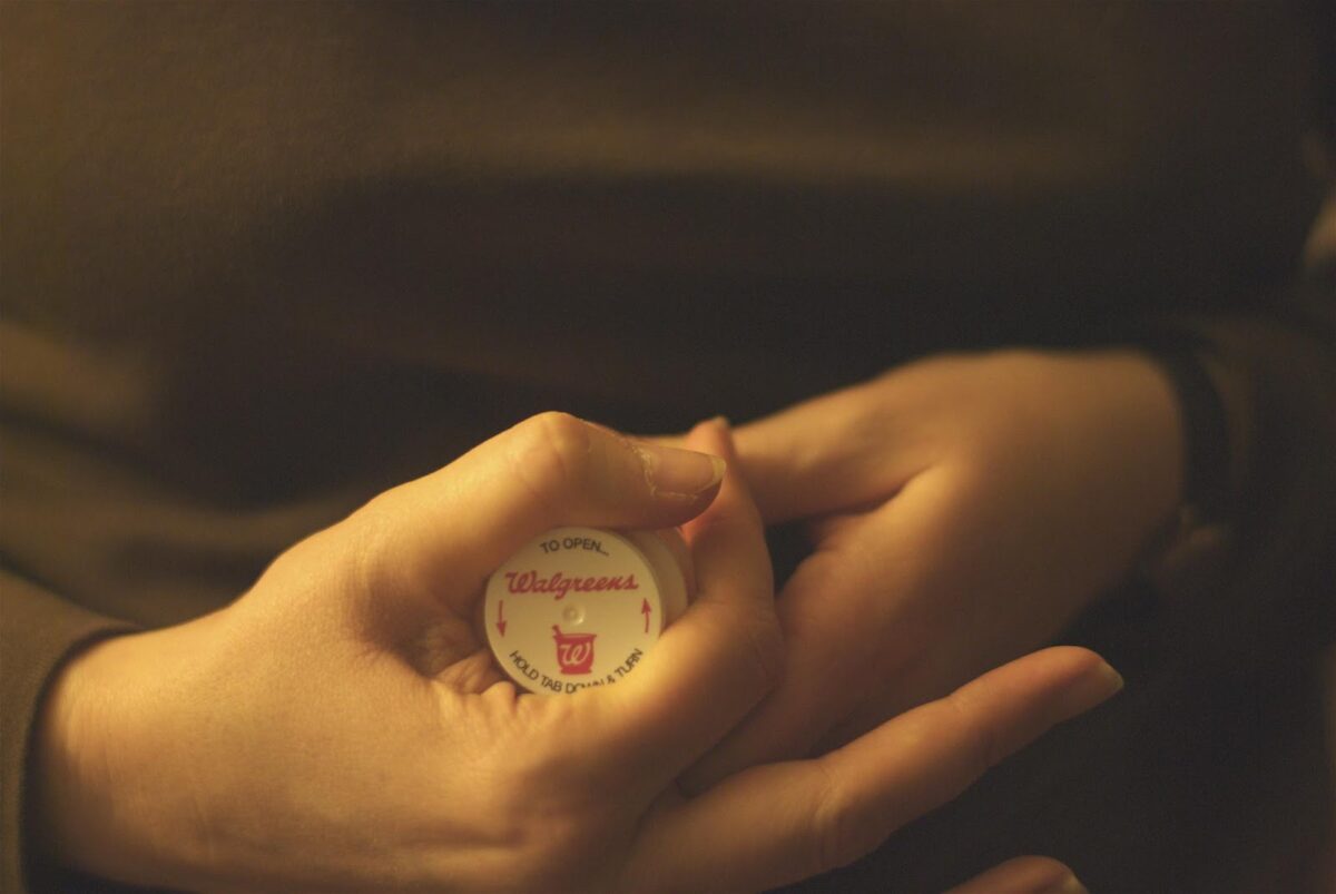 person holding Rx bottle, with cap facing camera