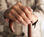 hands with signs of age resting on a cane